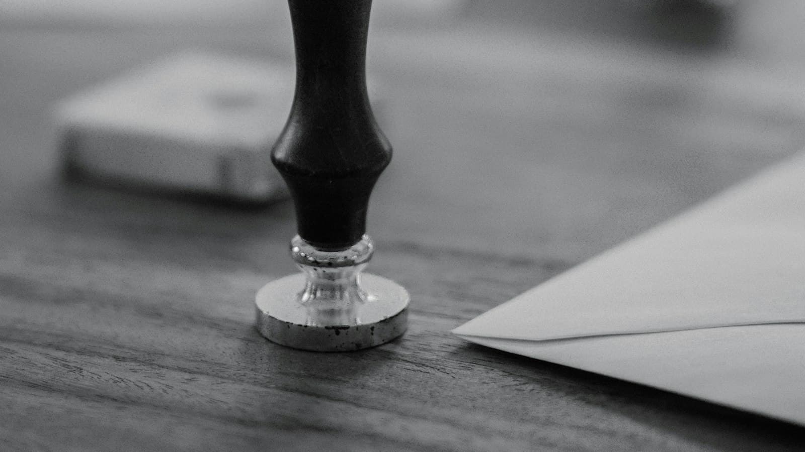 An official stamp resting on a wooden desk beside an envelope